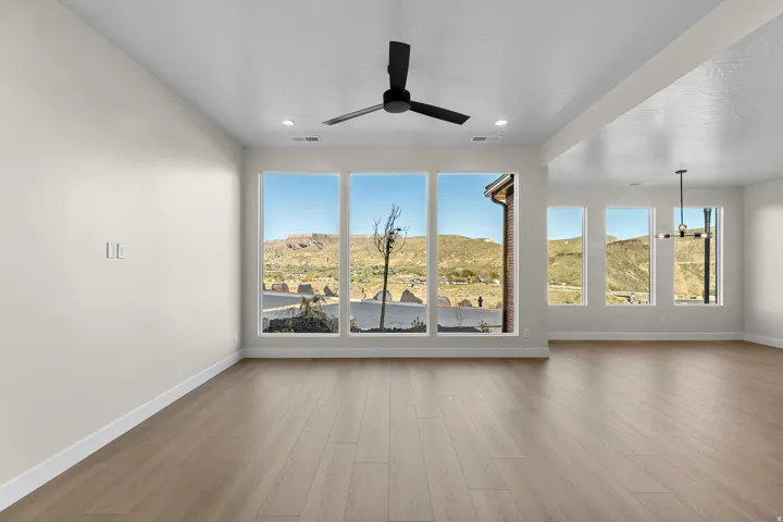 Spacious room featuring expansive windows with mountain scenery, wood-finish flooring, a contemporary ceiling fan, and recessed lighting