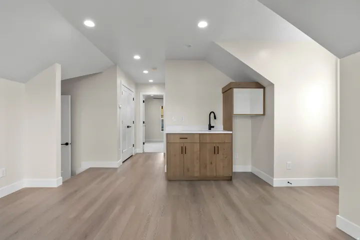 Built-in wet bar featuring wood-finish cabinetry, a light-toned countertop, and a matte black faucet