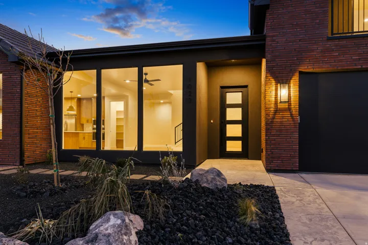 Modern facade featuring a dark brick exterior, large picture windows, and a sleek black entry door with frosted glass panels