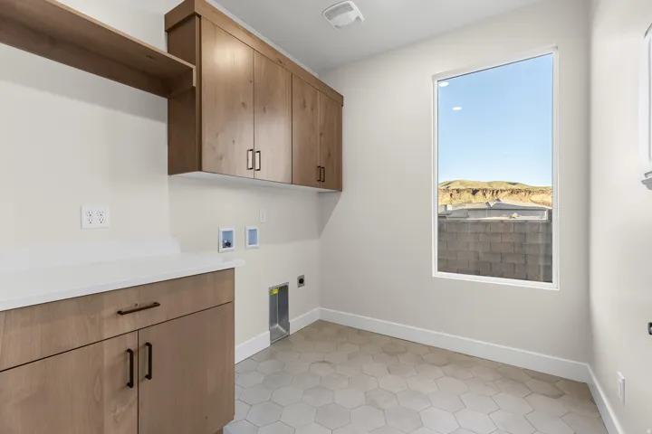 Utility area featuring ample cabinetry, integrated shelving, and a large window