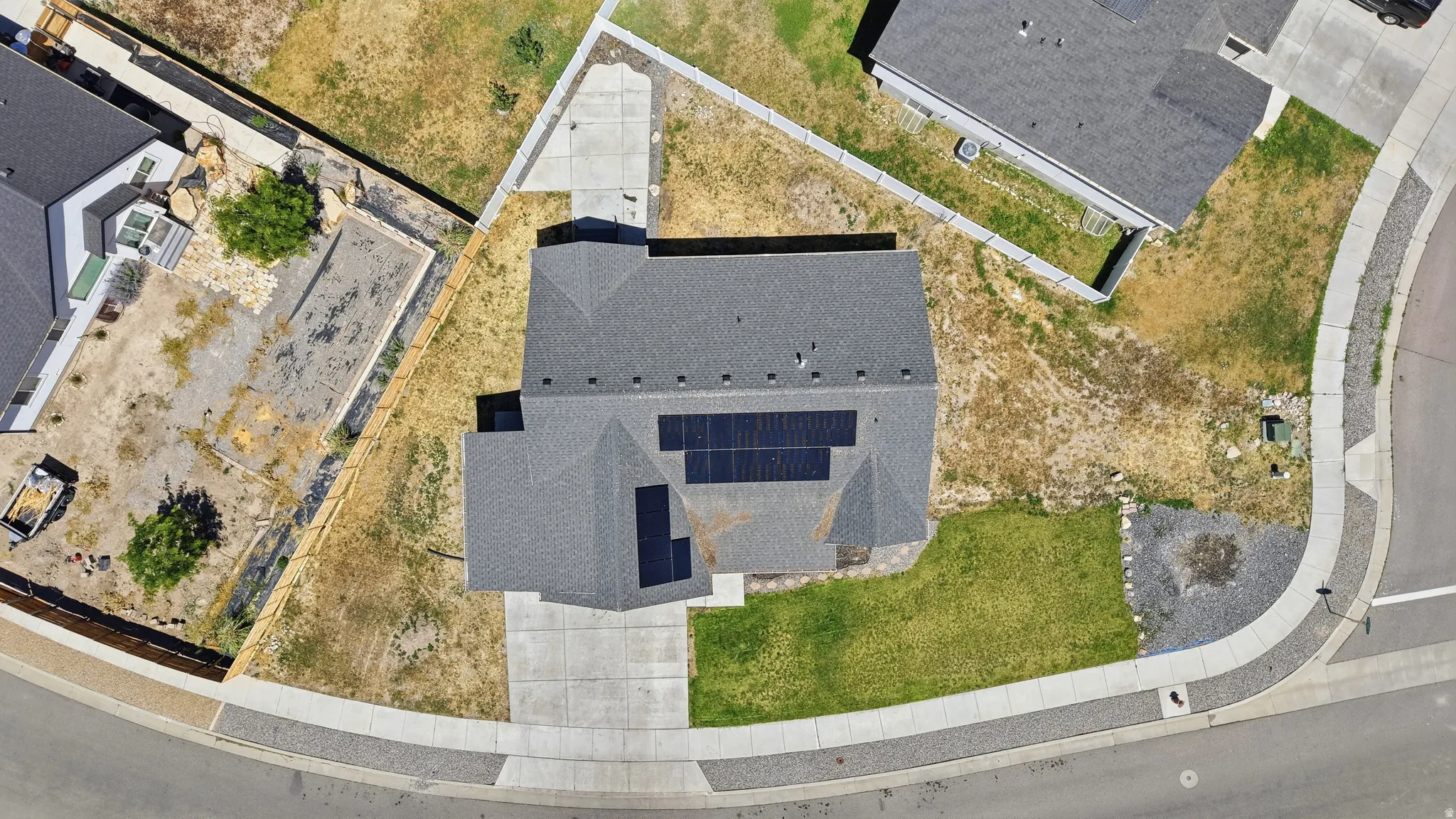 Overhead property view featuring a gray shingled roof with integrated solar panels