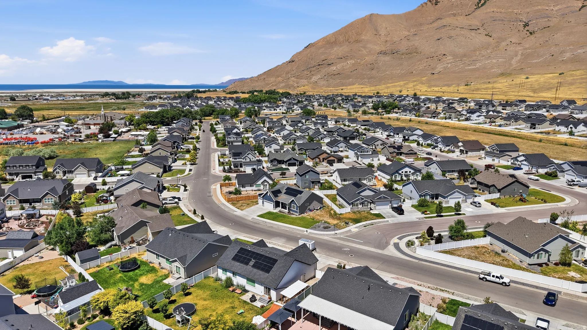 Expansive residential neighborhood with varied home styles, paved streets, and mountainous terrain in the background