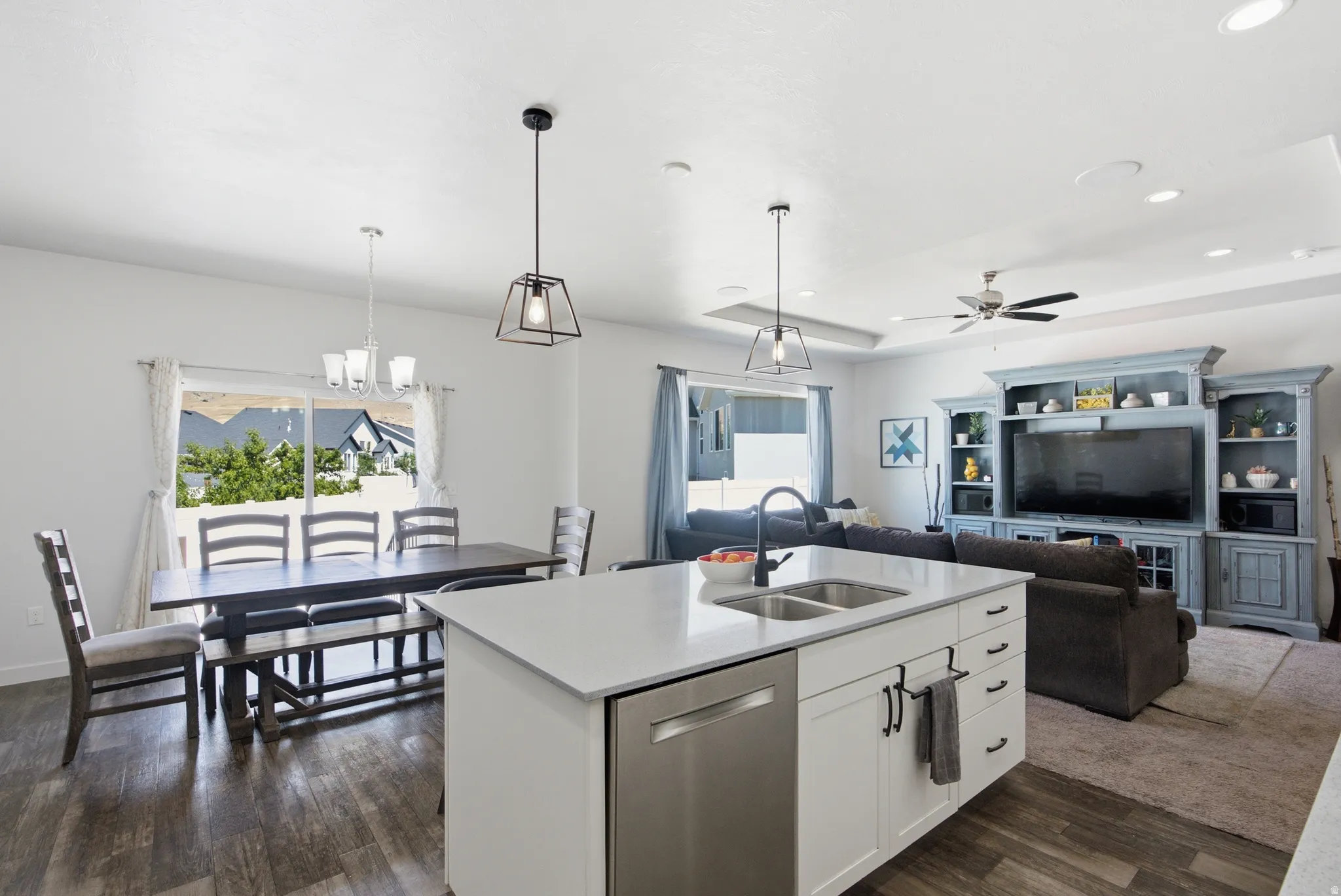 Open-concept living space featuring a white kitchen island with an undermount double sink, stainless steel dishwasher, and quartz-finish countertop
