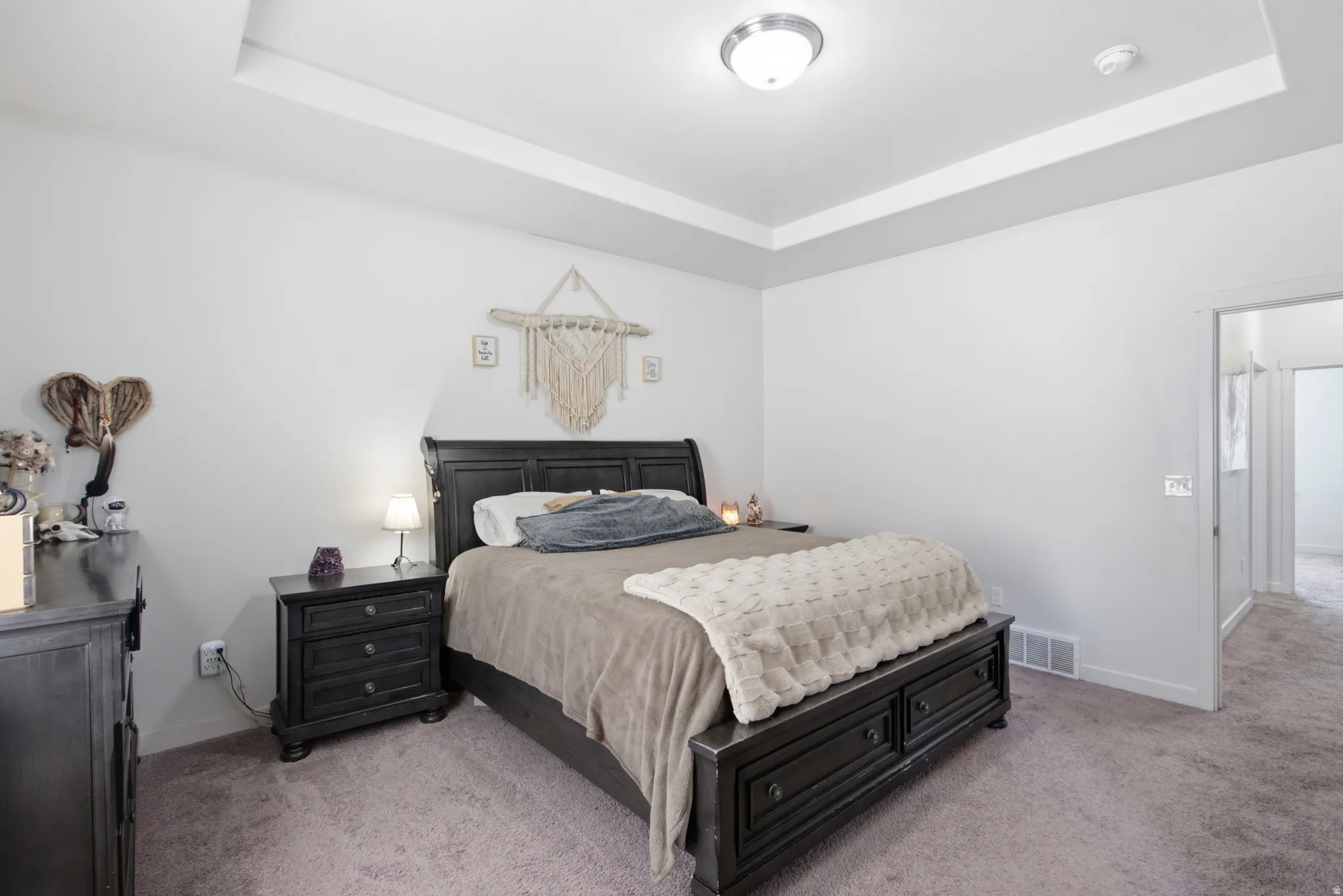 Bedroom featuring a tray ceiling, recessed lighting, and soft gray carpet flooring