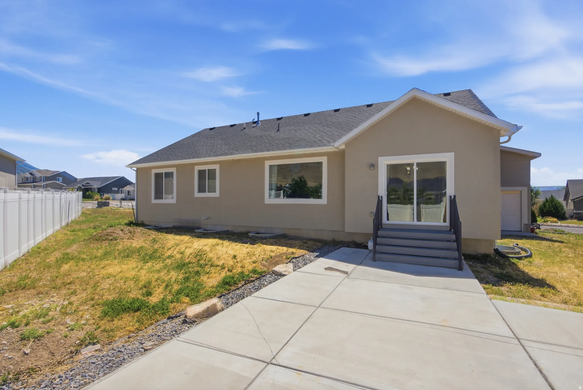 Rear exterior featuring a sliding glass door, multi-pane windows, a concrete patio, and a privacy fence