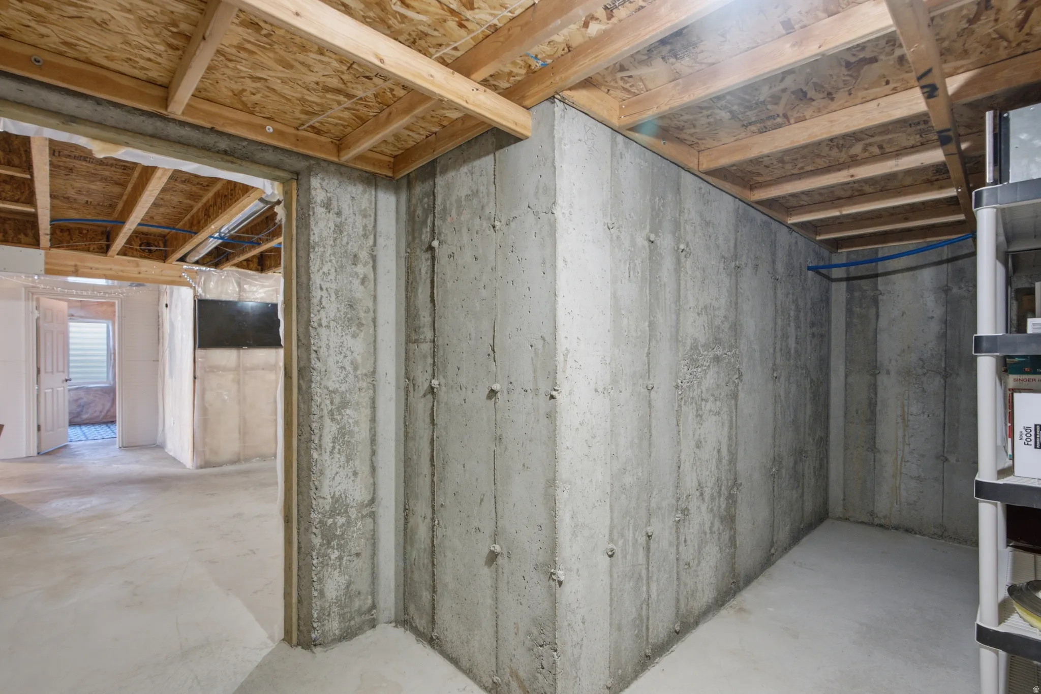 Unfinished basement featuring concrete walls and exposed wood ceiling joists