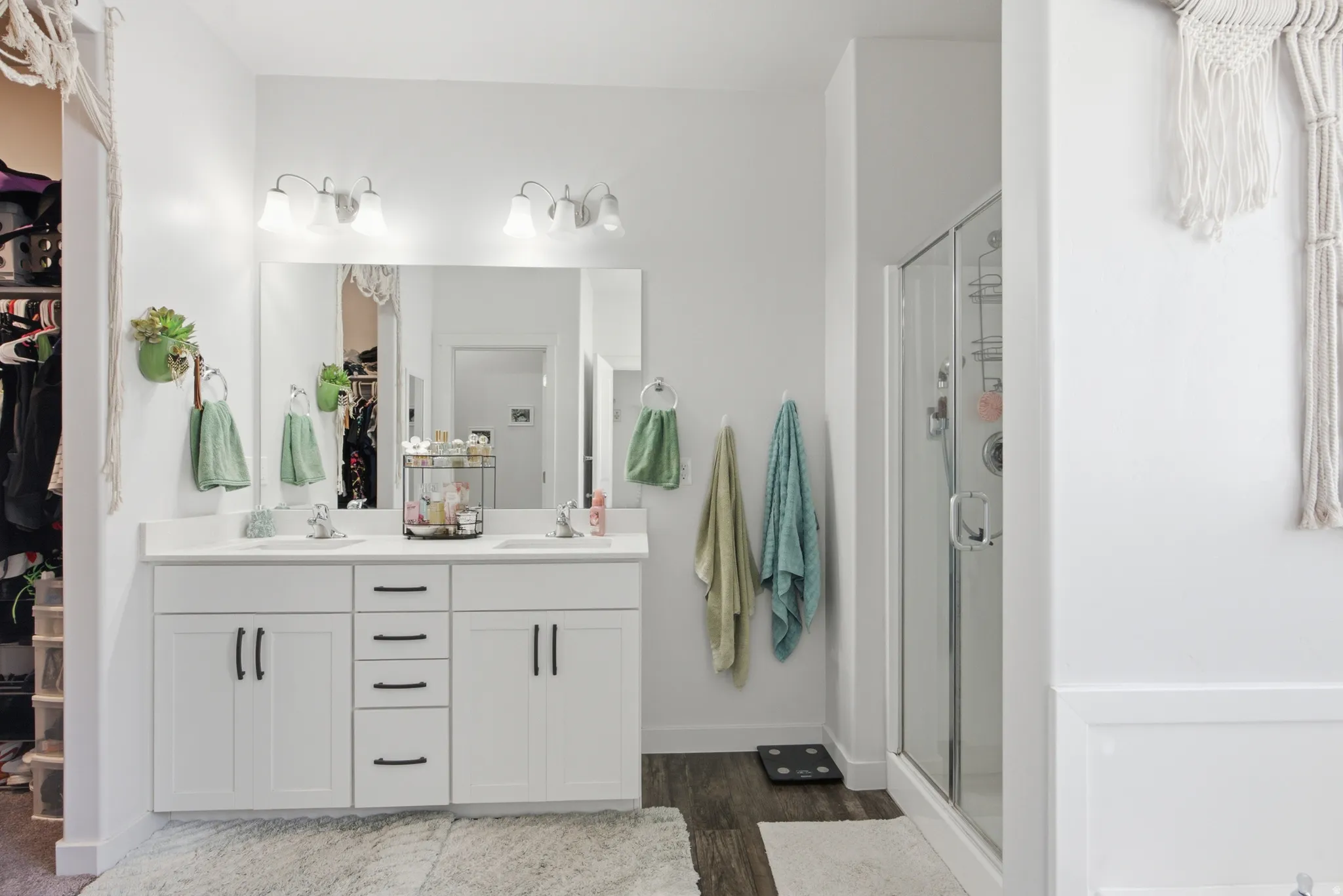 Double vanity with white cabinetry, matte black hardware, and an expansive mirror