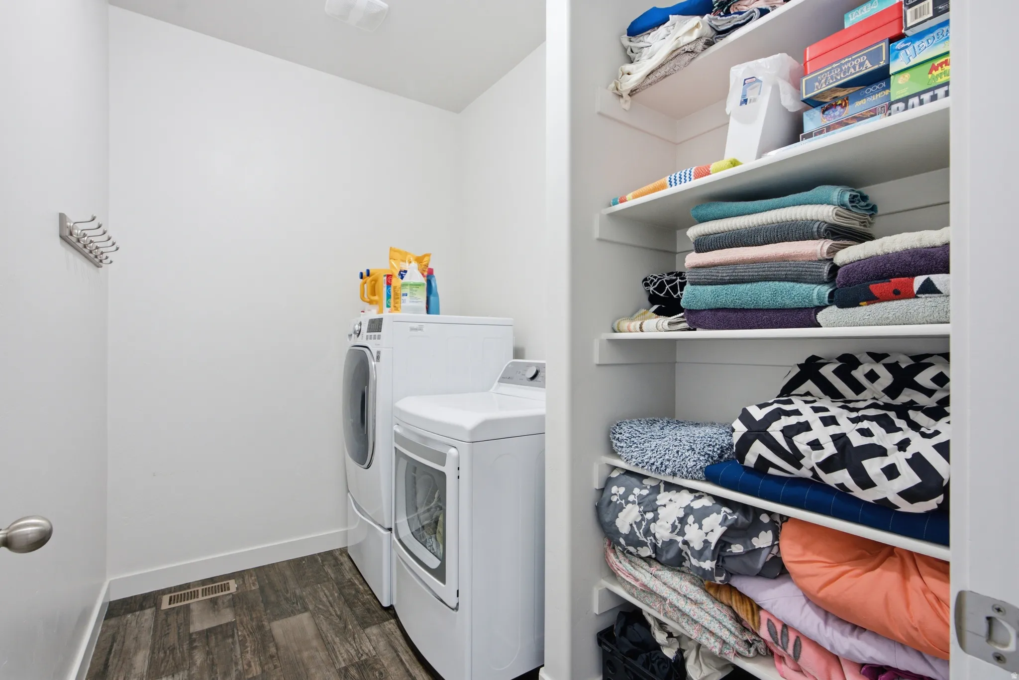 Dedicated laundry area featuring wood-finish flooring and a white color palette