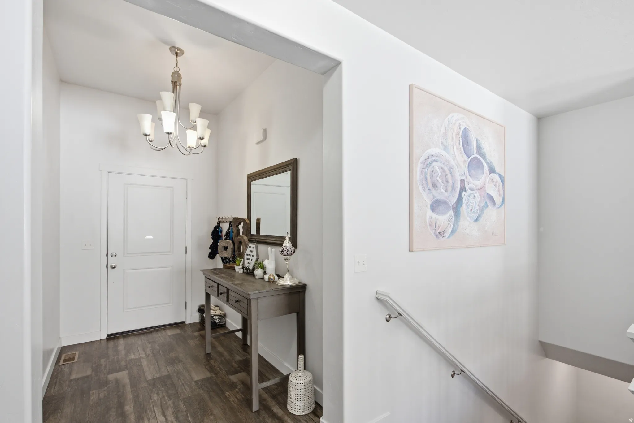Entryway featuring wood-finish flooring, a white paneled entry door, and a multi-arm ceiling chandelier