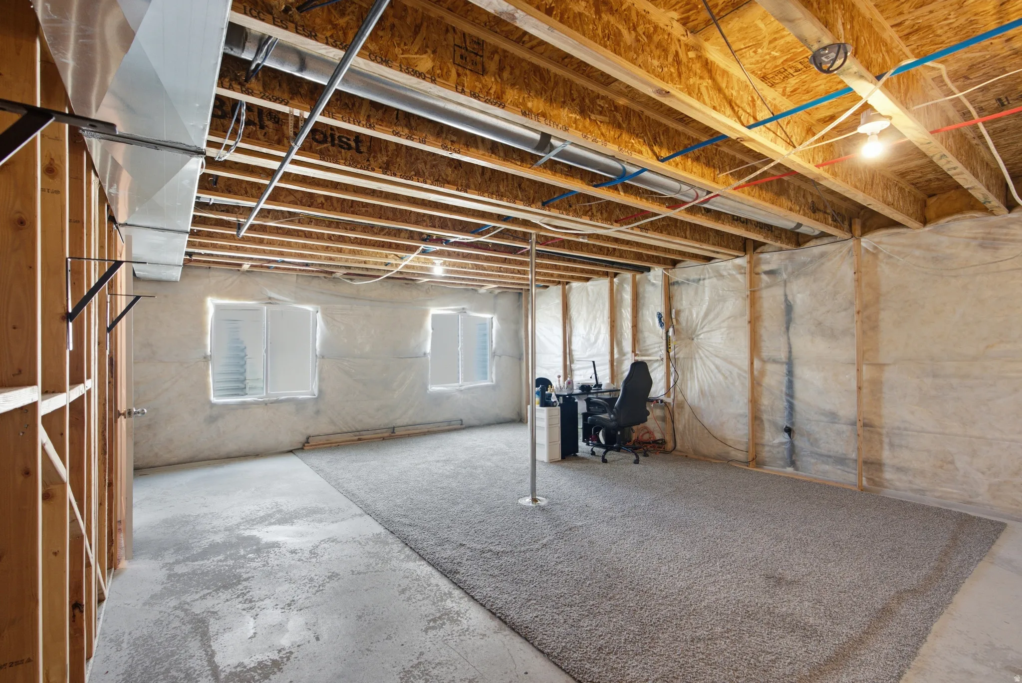 Unfinished basement featuring exposed wood joists, concrete flooring, and partial carpeting