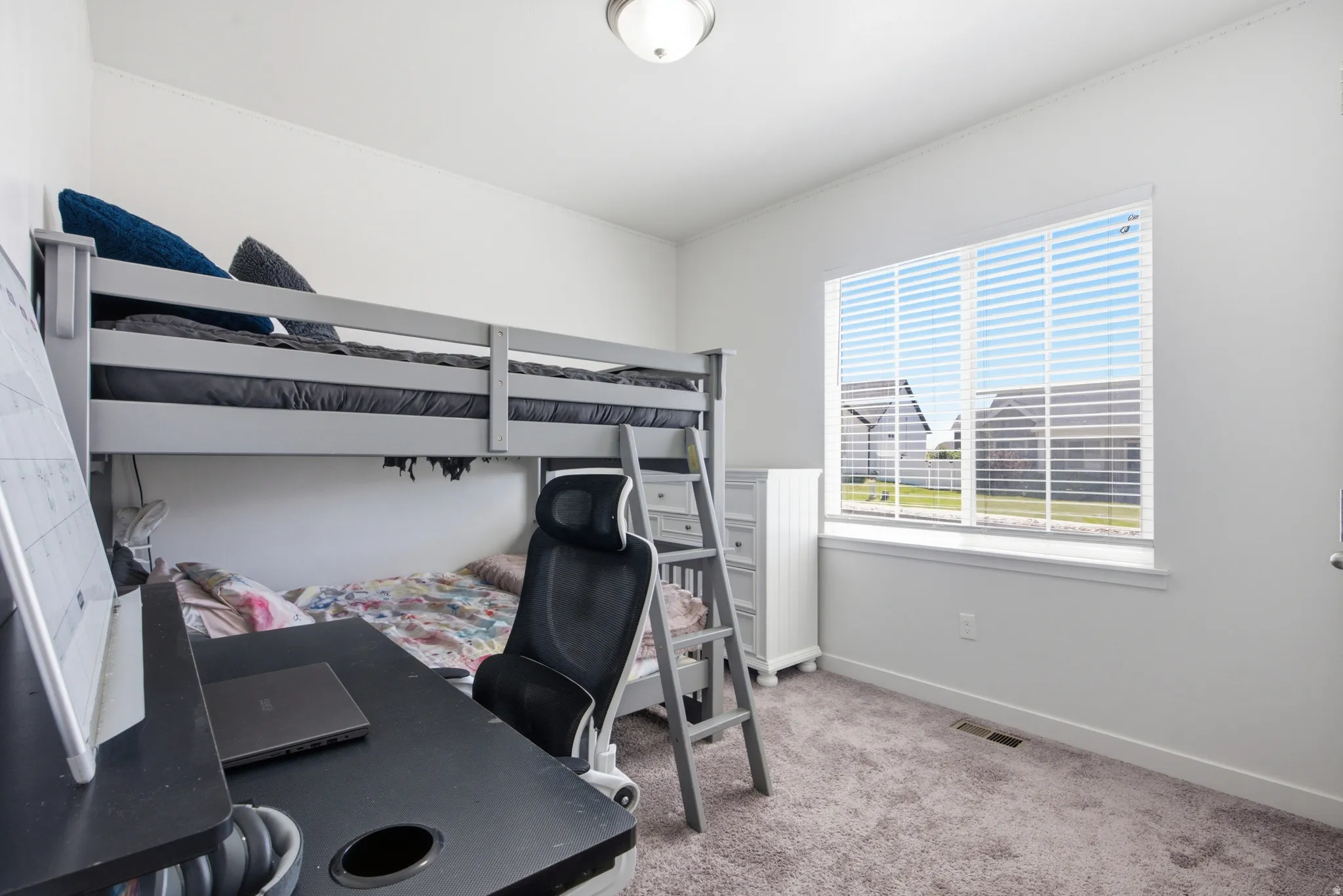 Bright room featuring a large window with horizontal blinds, neutral wall paint, and gray carpet flooring