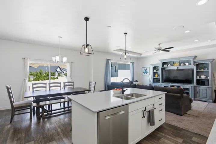 Open-concept living space featuring a white kitchen island with an undermount double sink, stainless steel dishwasher, and quartz-finish countertop