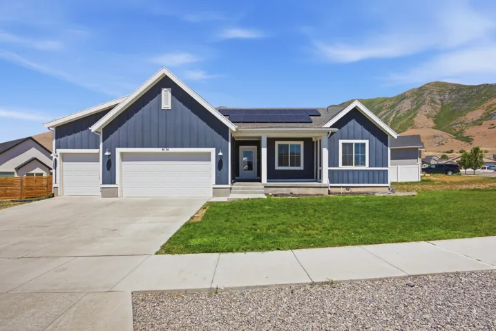 Single-story residence featuring a blue board and batten facade with white trim, a covered front porch, and a two-car garage