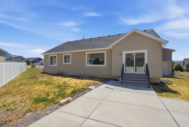 Rear exterior featuring a sliding glass door, multi-pane windows, a concrete patio, and a privacy fence