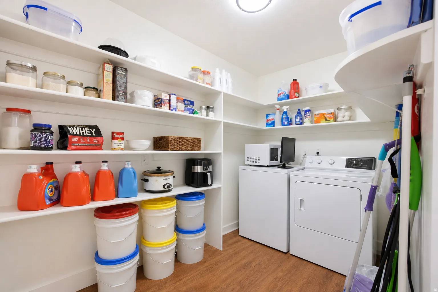 Dedicated laundry room featuring a washer and dryer, extensive built-in shelving, wood-finish flooring, and overhead lighting