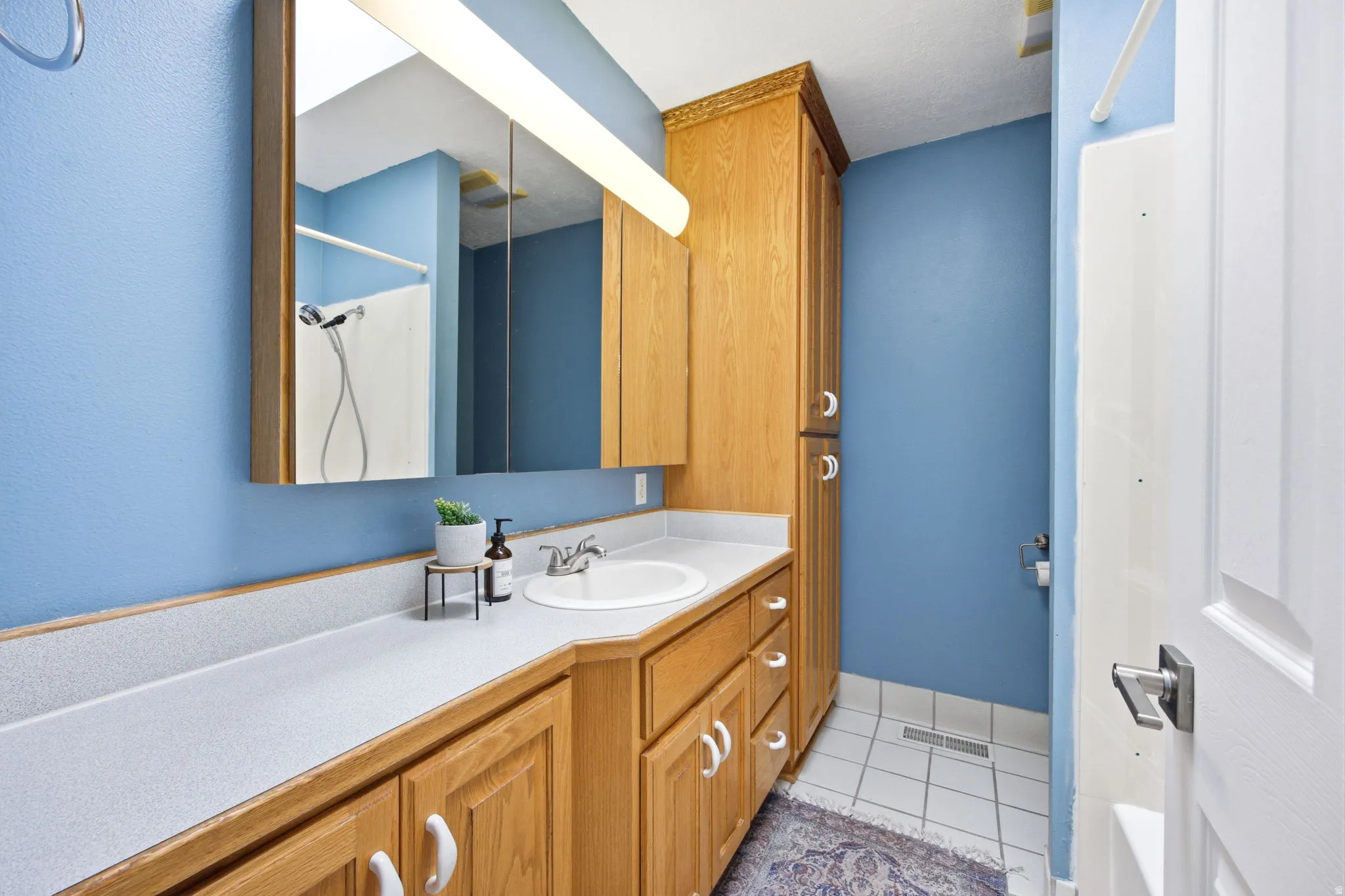 Bathroom featuring a single vanity with an integrated sink, laminate countertop, and wood-finish cabinetry