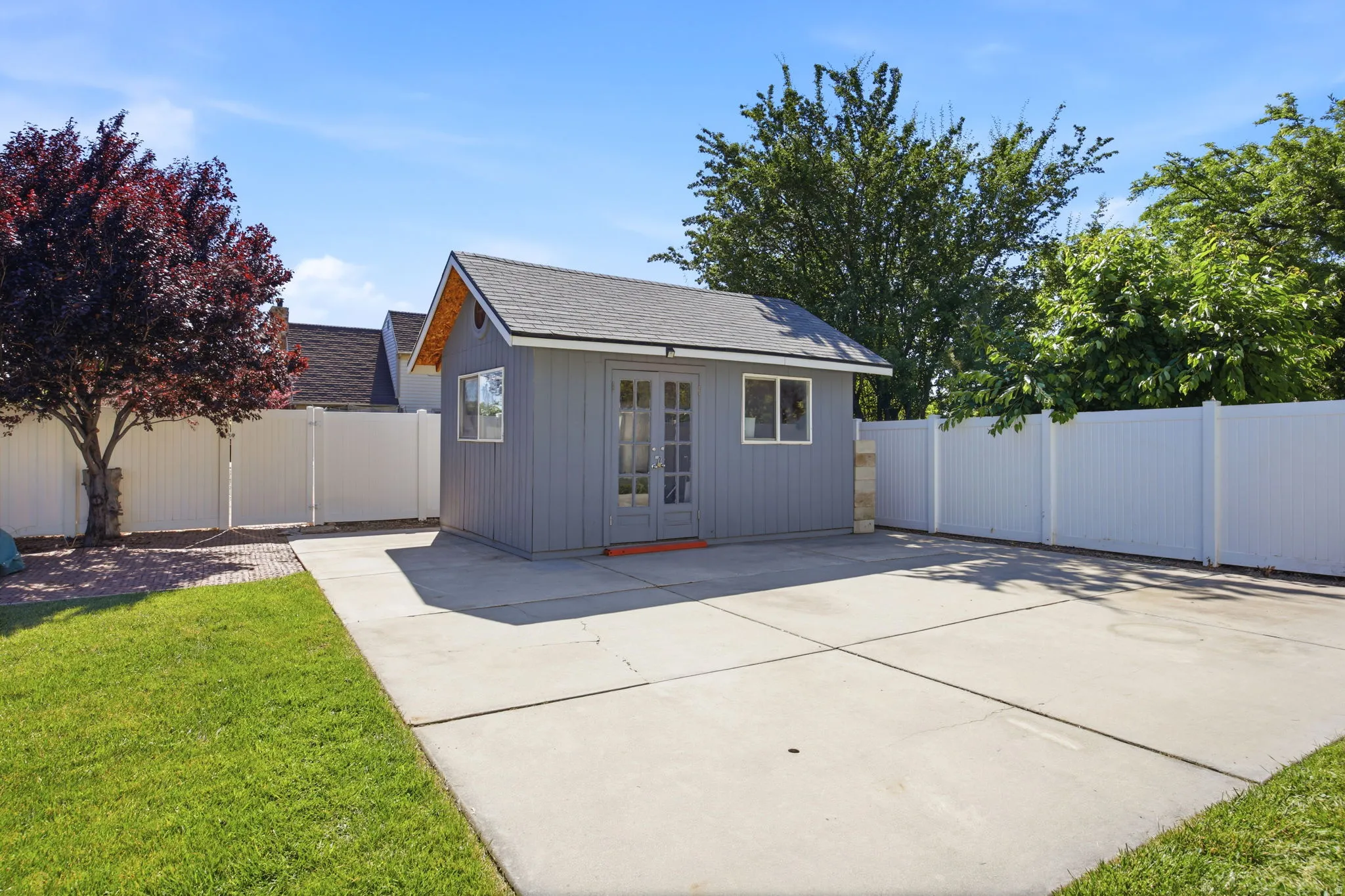 Detached shed with double doors and two windows, set on a concrete pad