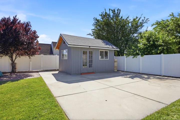 Detached shed with double doors and two windows, set on a concrete pad