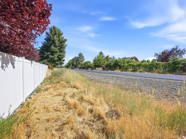 White privacy fence bordering a gravel roadside