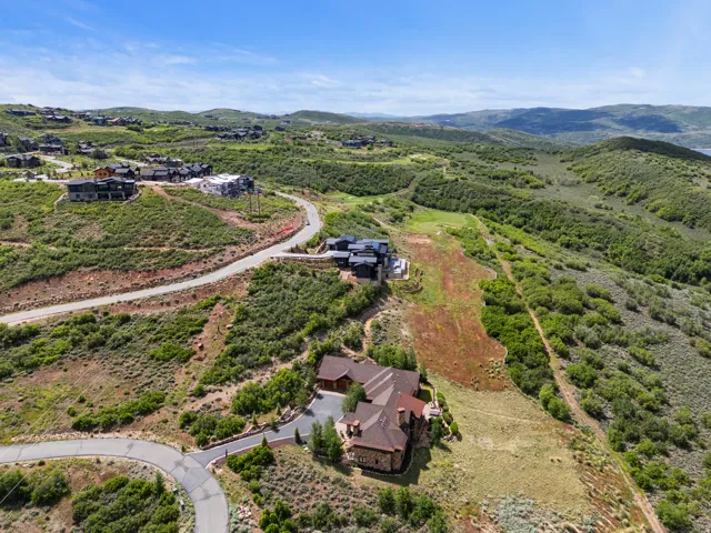 Hillside property featuring a stone and timber exterior, an attached multi-car garage, and a paved driveway