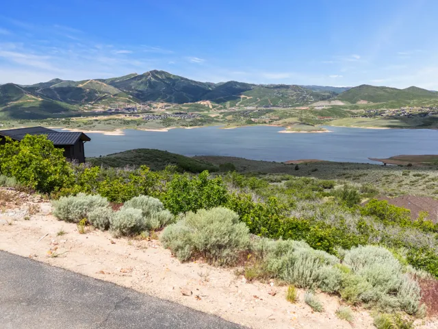 Expansive mountain and lake scenery with a partial view of a modern dark-toned structure featuring a black metal roof