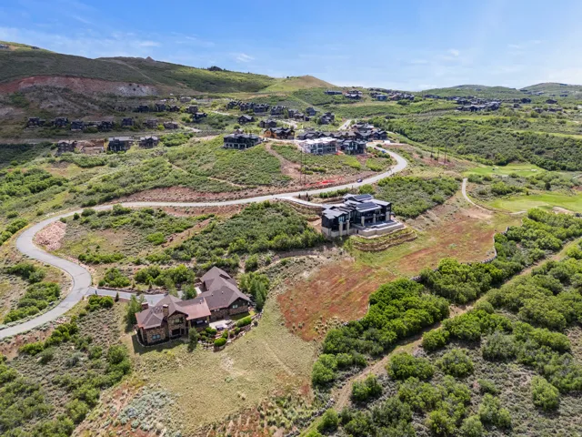 Aerial perspective of a hillside residential setting with multiple properties, winding paved roads, and natural landscaping