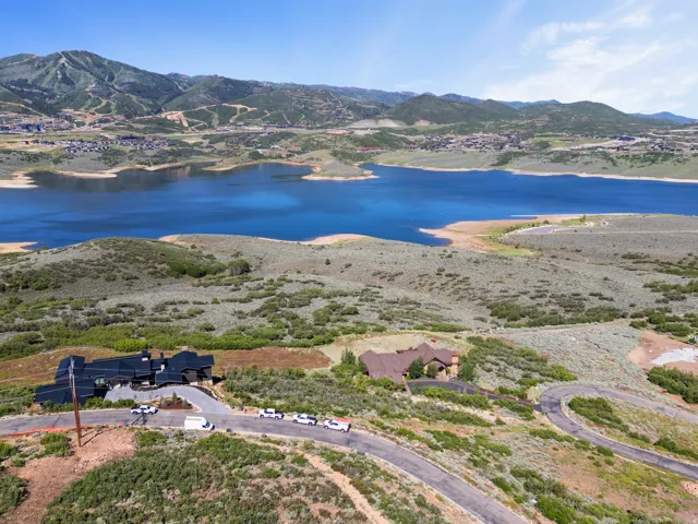 Expansive landscape featuring a large body of water, distant mountains with visible ski trails, and multiple residential structures