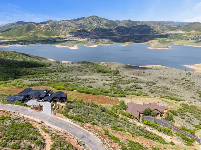 Expansive mountain-side property featuring a sweeping lake backdrop and a paved private drive