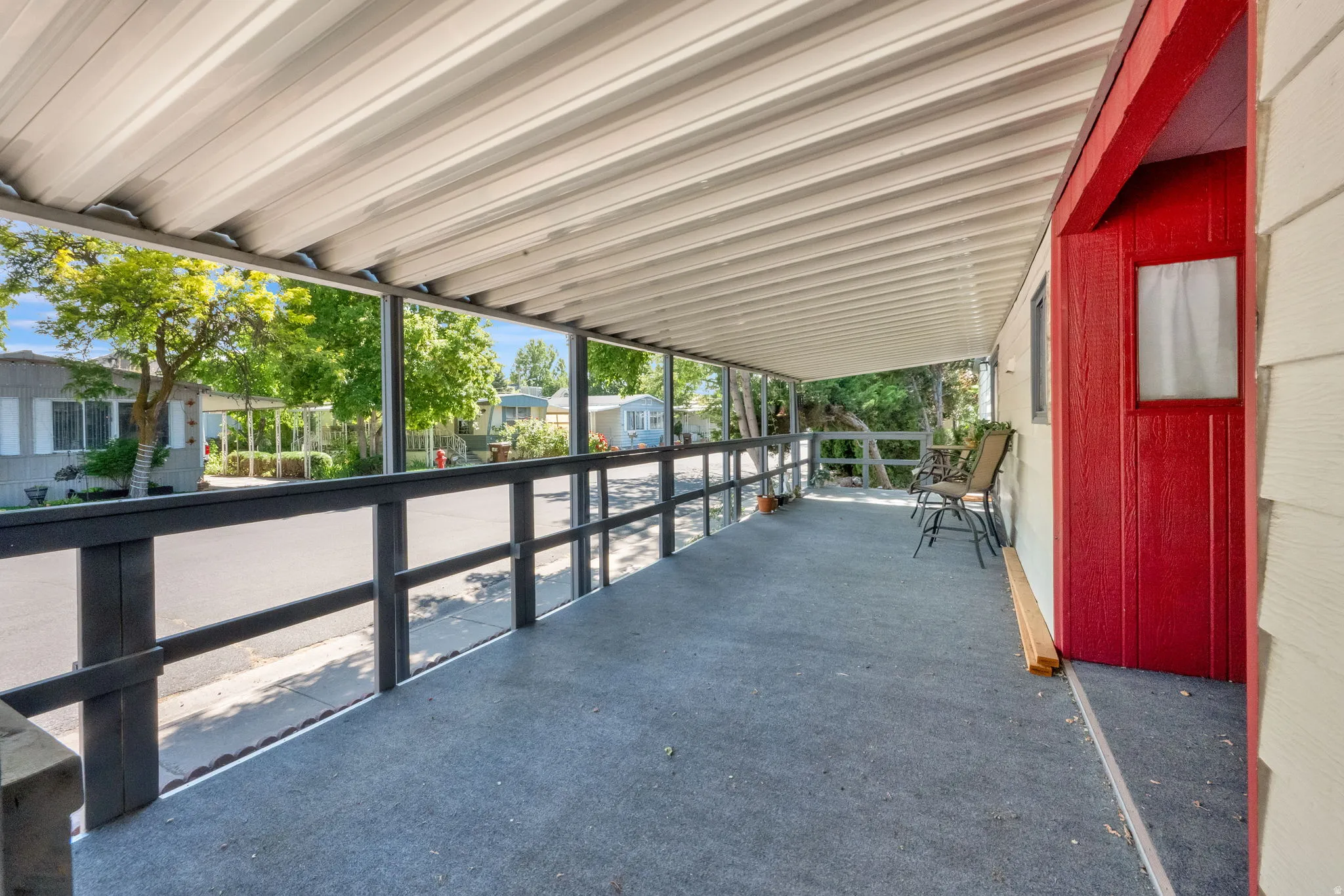 Covered porch featuring a metal roof, dark-stained railing, and a red entry door with a small window