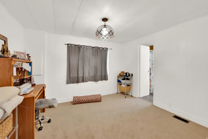 Carpeted room featuring white paneled walls and a decorative ceiling light fixture
