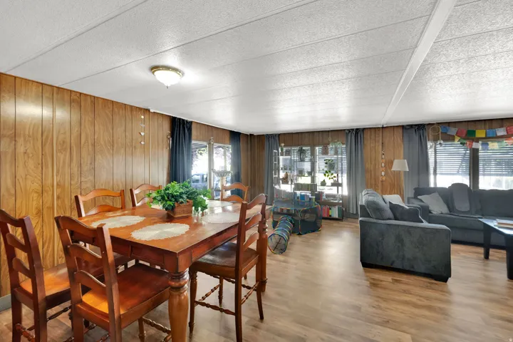 Open-concept living space featuring wood-finish paneling, wood-finish flooring, and multiple windows with blinds