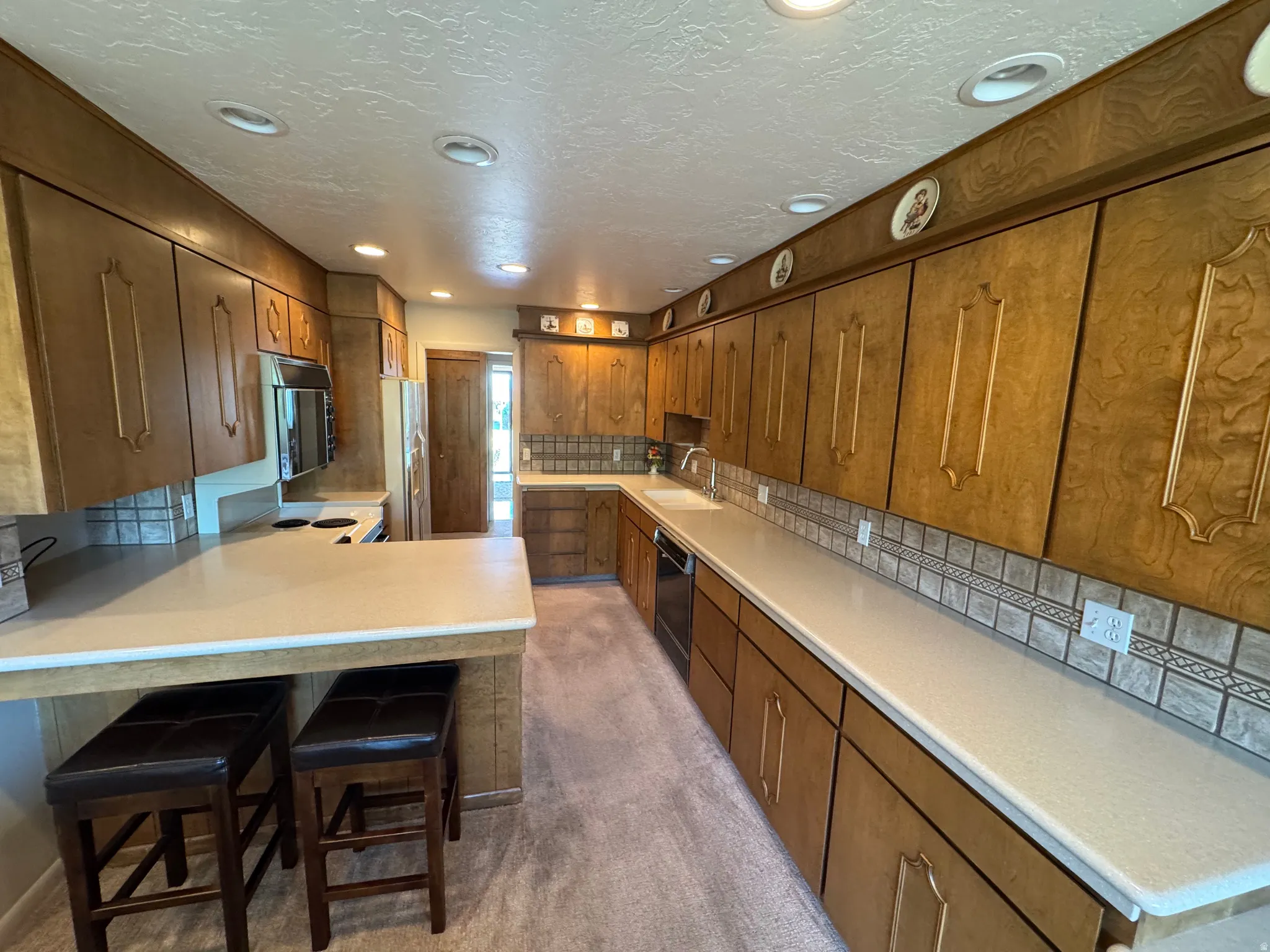 Kitchen featuring extensive wood cabinetry, light-toned countertops, and a tiled backsplash