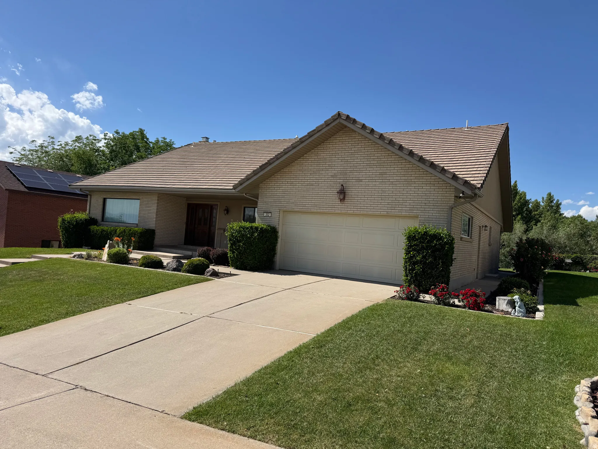 Ranch-style residence featuring a tile roof, brick and stucco exterior, and an attached garage with a panel door