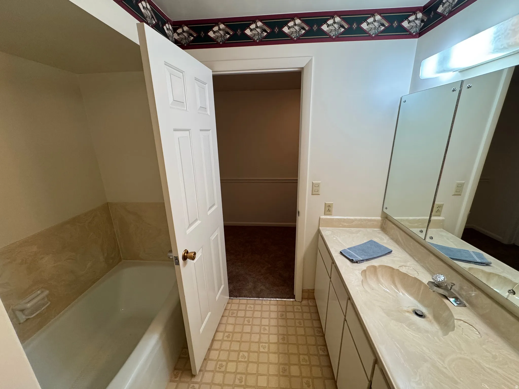 Bathroom featuring a vanity with an integrated sink, a rectangular mirror, and a wall-mounted light fixture