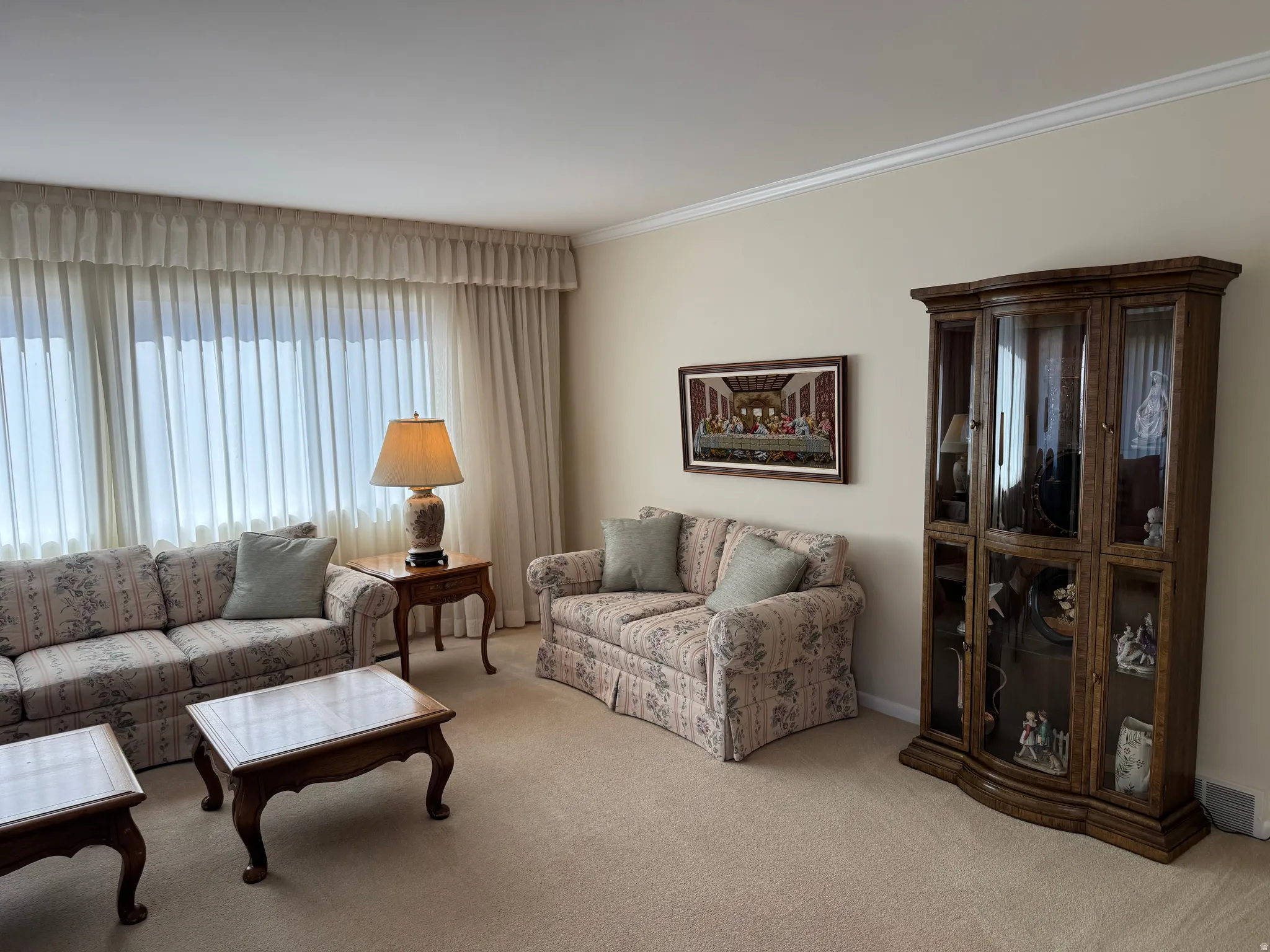 Carpeted living space featuring a large picture window with extensive window treatments