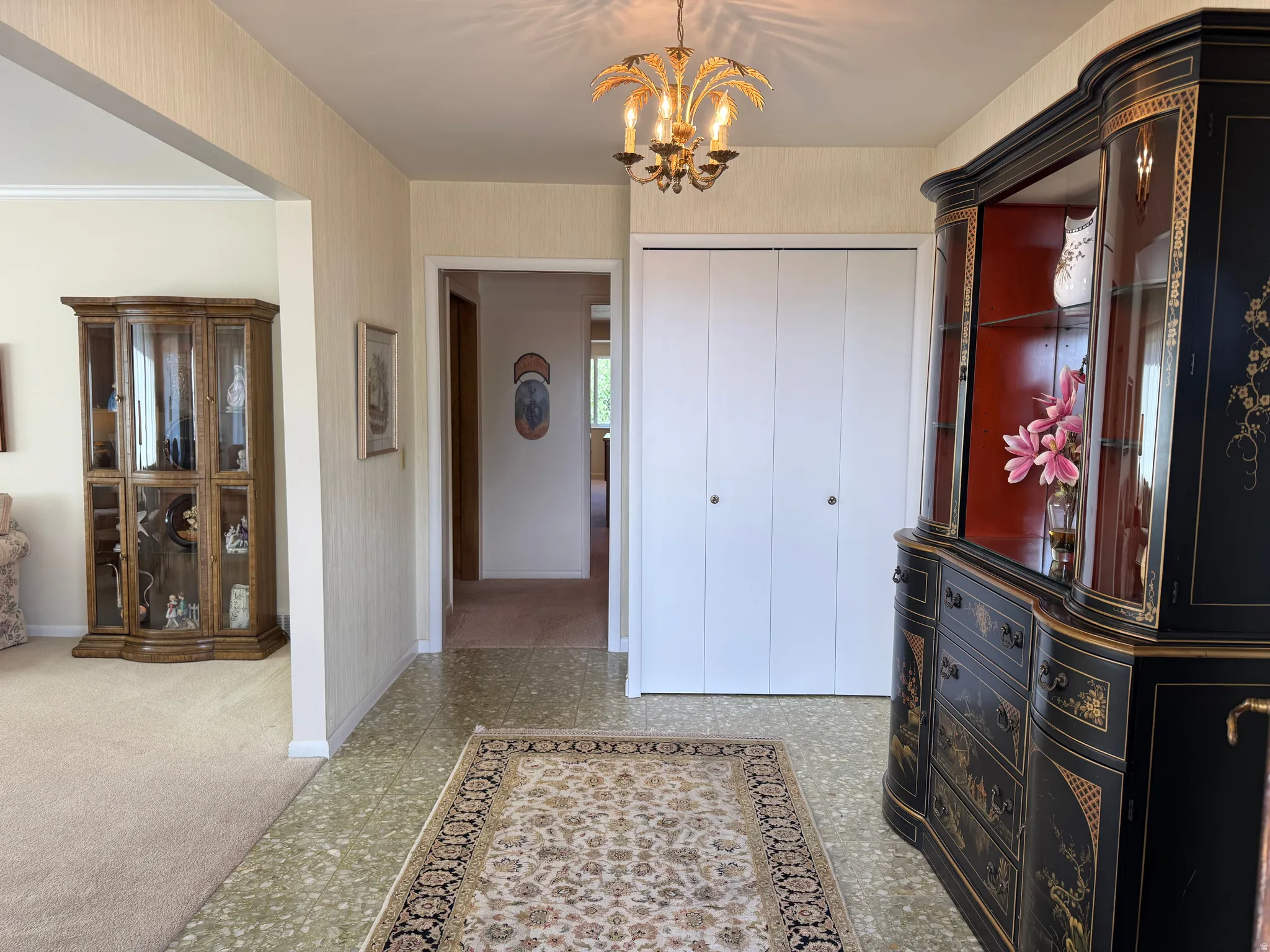 Entry foyer featuring patterned tile flooring, a decorative chandelier, and white bifold closet doors