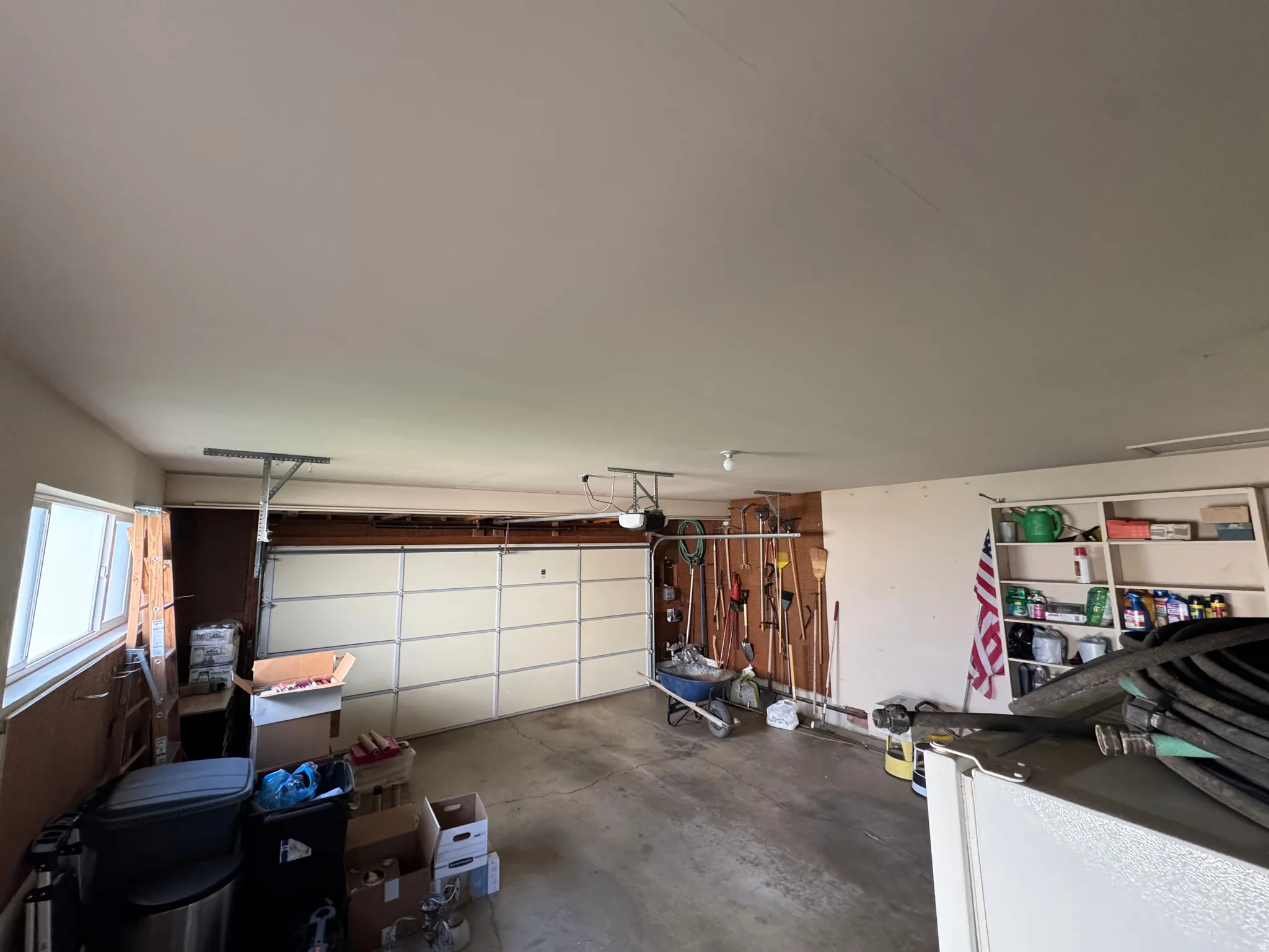 Interior garage space featuring a paneled garage door, exposed wood beam framing, and built-in shelving