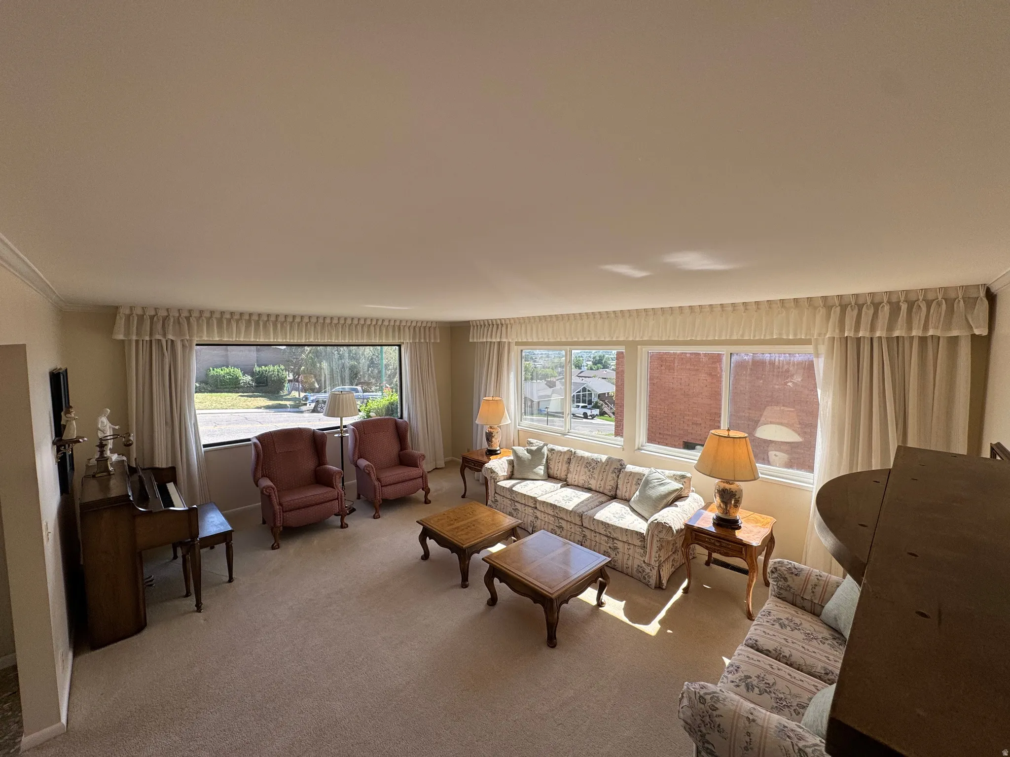 Spacious living area featuring expansive windows, neutral carpeting, and crown molding