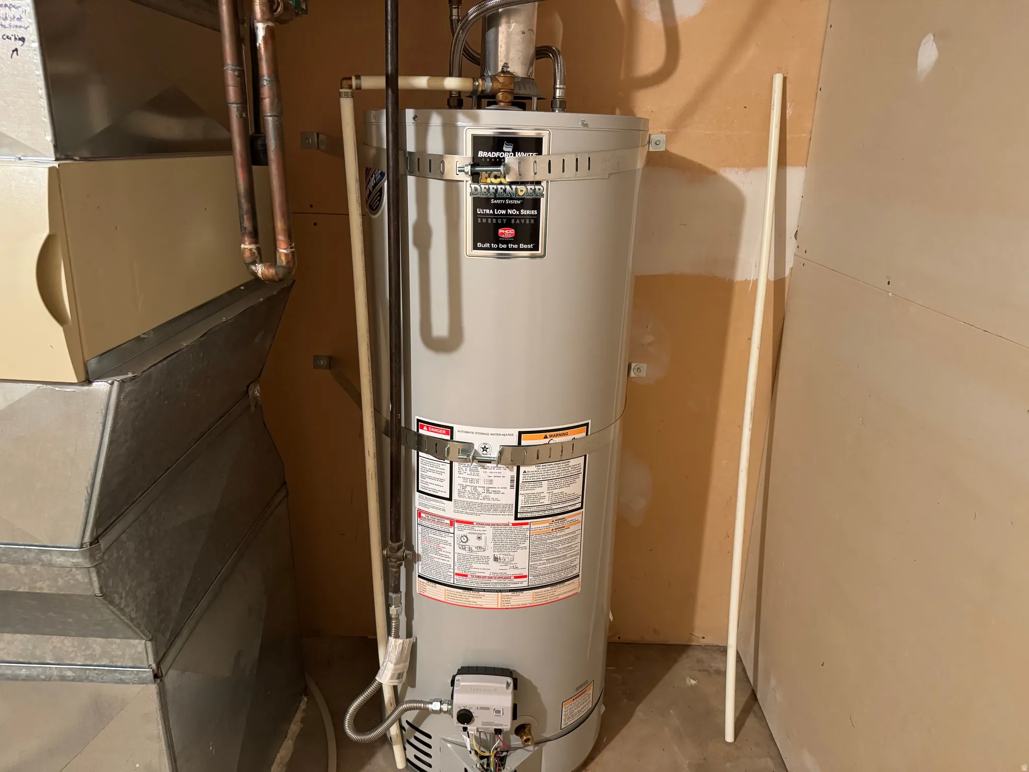 Water heater with visible piping and adjacent ductwork