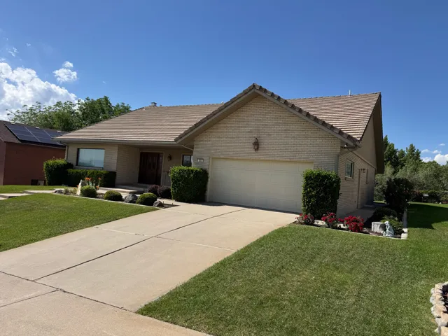 Ranch-style residence featuring a tile roof, brick and stucco exterior, and an attached garage with a panel door