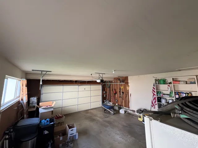 Interior garage space featuring a paneled garage door, exposed wood beam framing, and built-in shelving