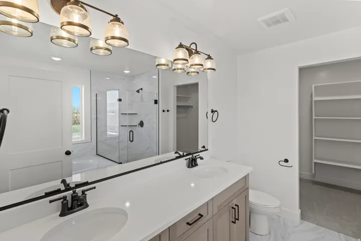Dual vanity with white countertop and black fixtures, featuring a large mirror and overhead lighting