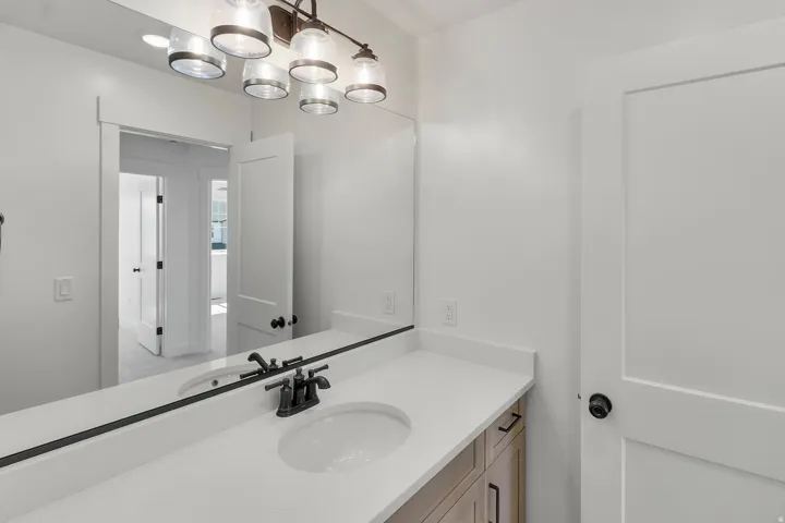 Bathroom vanity featuring a light-toned countertop, integrated sink, and dark-finished hardware