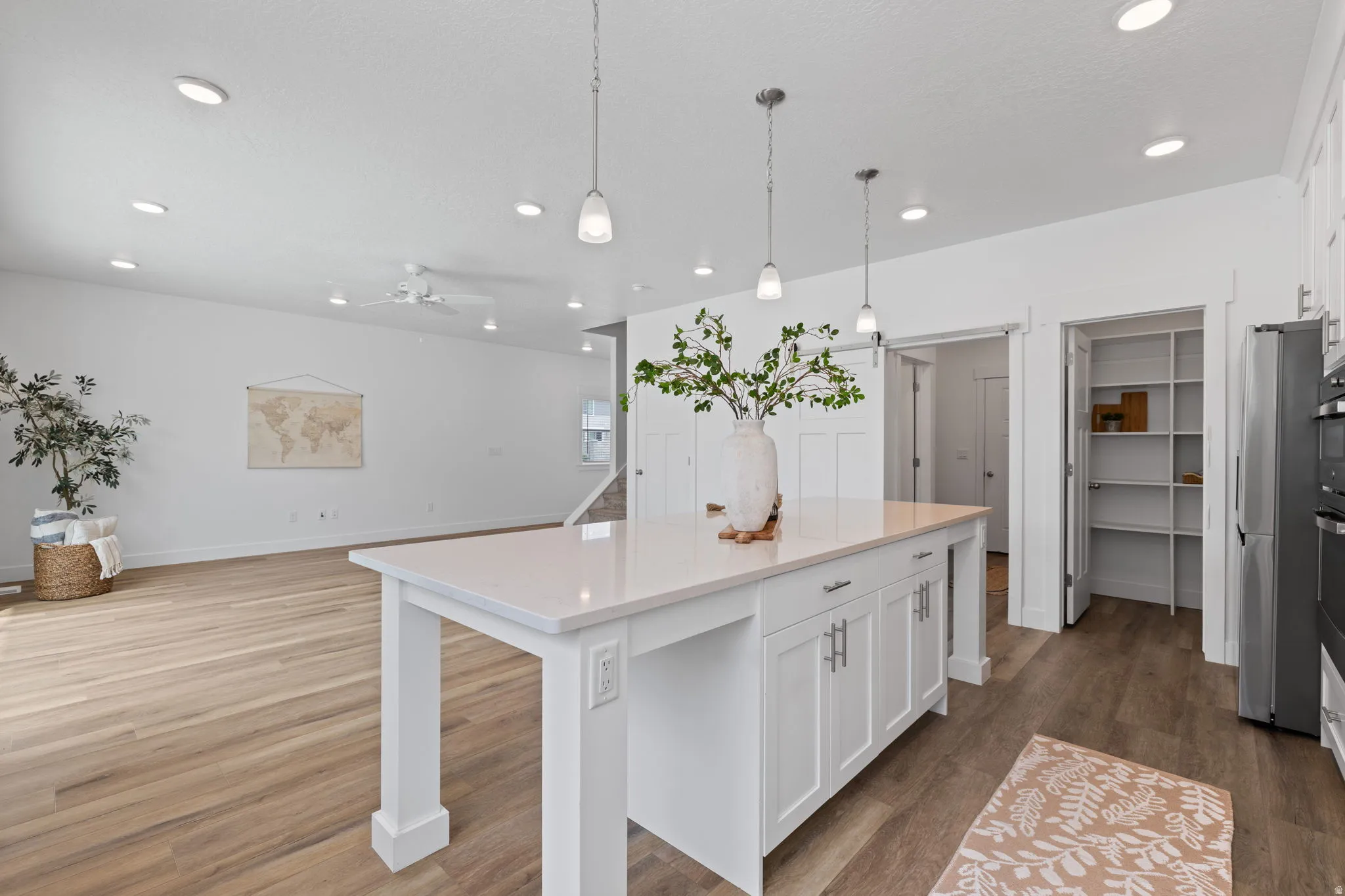 Kitchen island with a light-toned countertop, pendant lighting, and white cabinetry