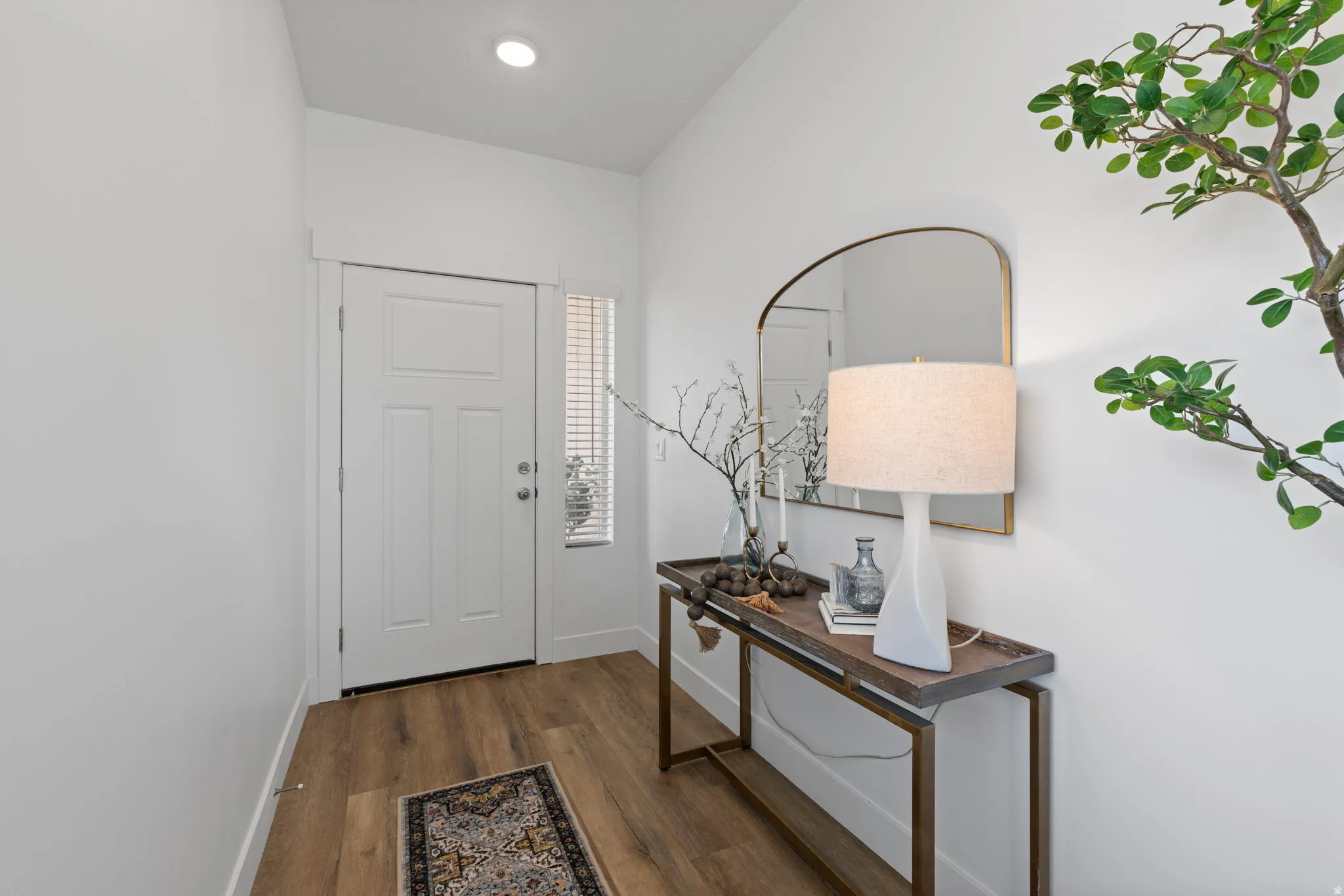 Entryway featuring wood-finish flooring, recessed lighting, and a white paneled door with a sidelight