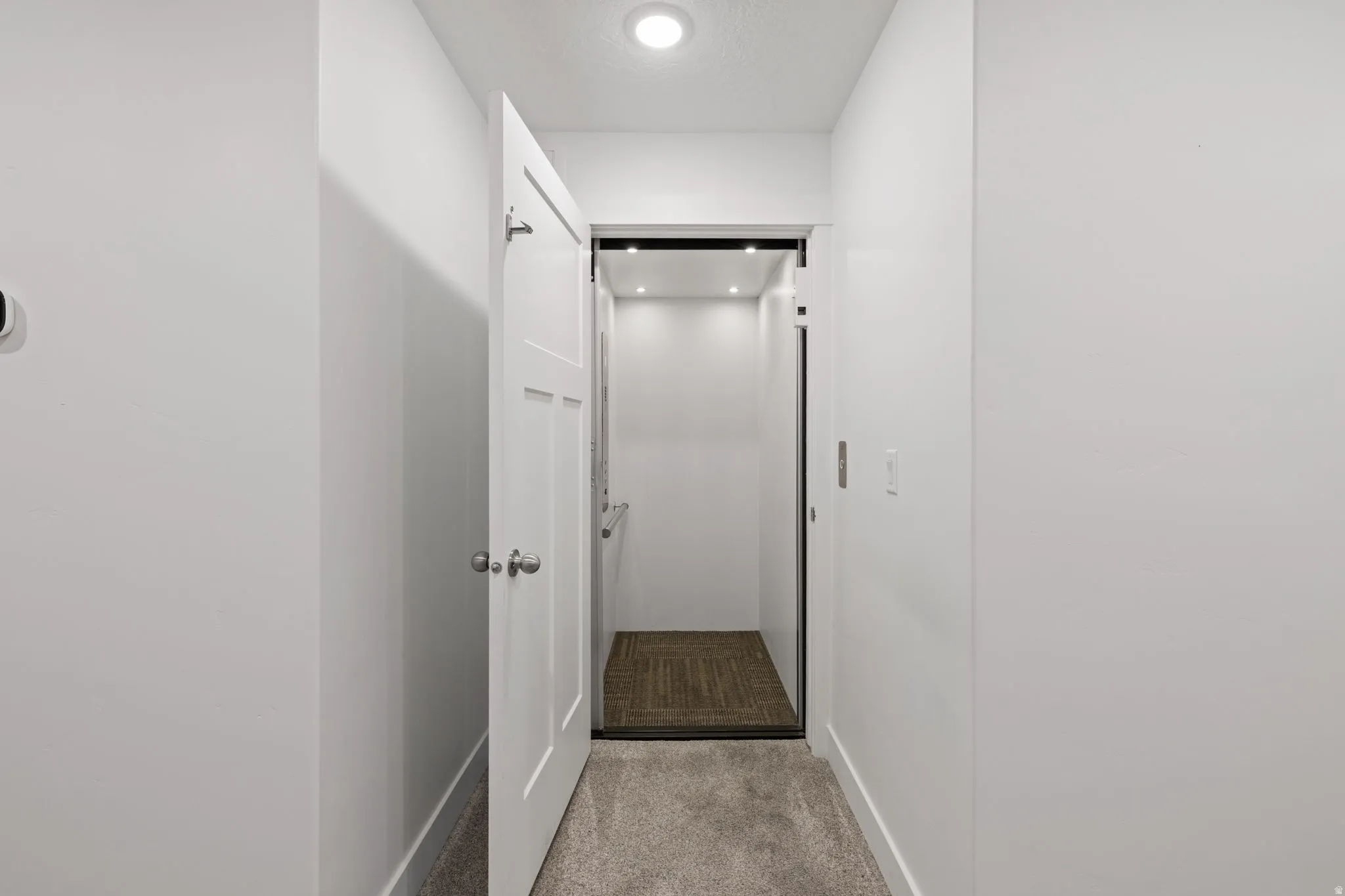 Interior residential elevator featuring recessed lighting, a grab bar, and a woven floor mat