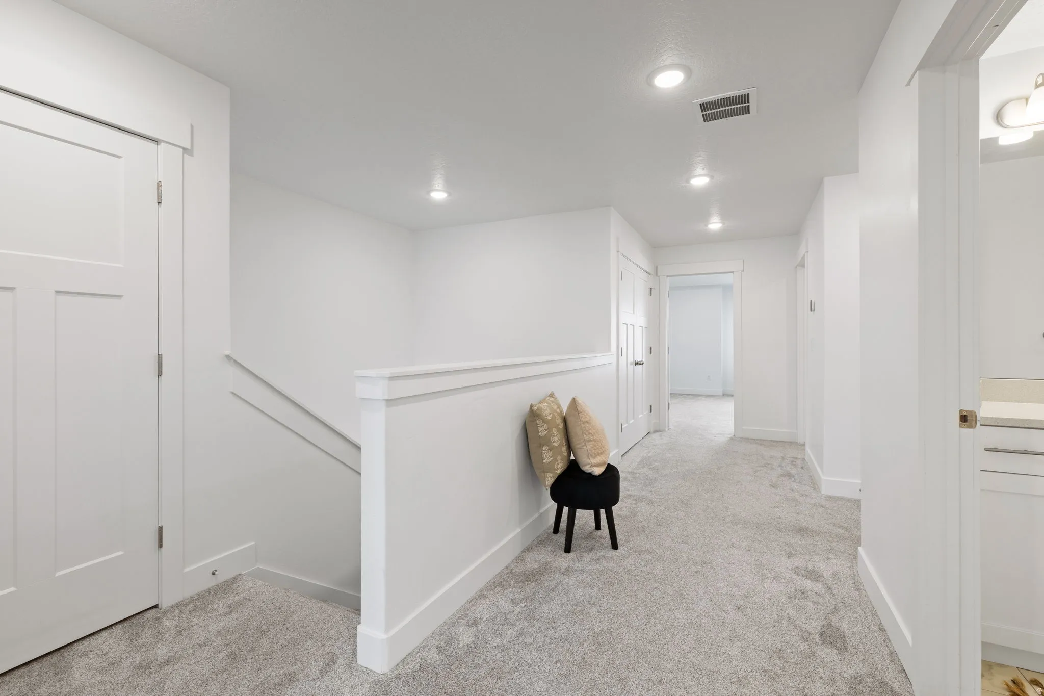 Hallway with light gray carpeting, white trim, and recessed lighting