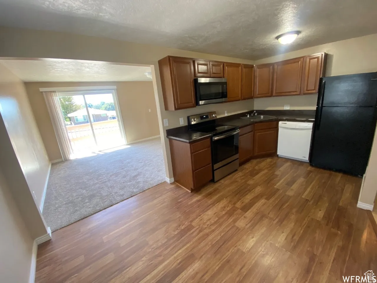 Kitchen featuring wood-finish flooring, dark countertops, and brown cabinetry