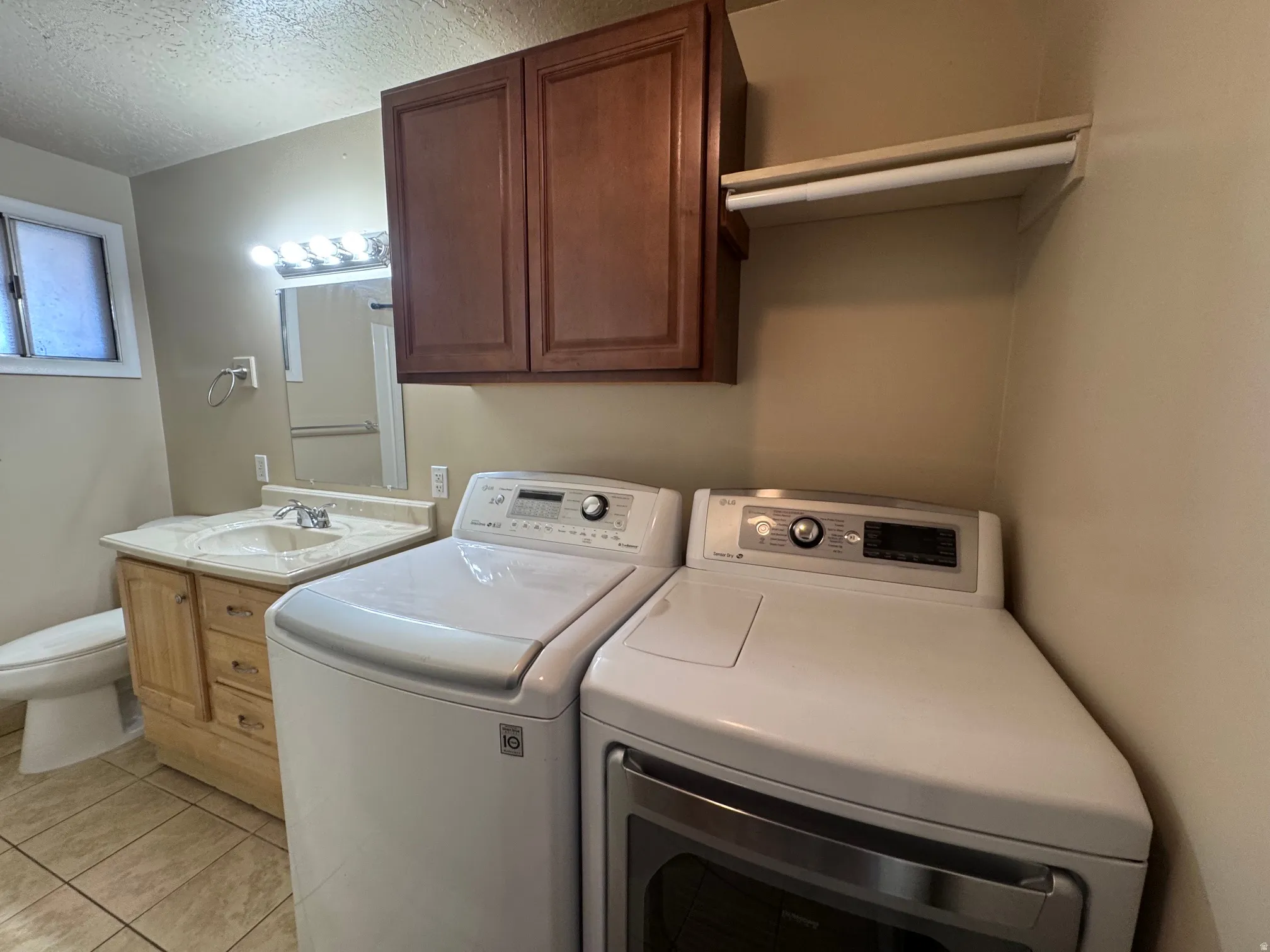 Laundry area featuring a side-by-side washer and dryer, adjacent to a vanity with an integrated sink and base cabinetry