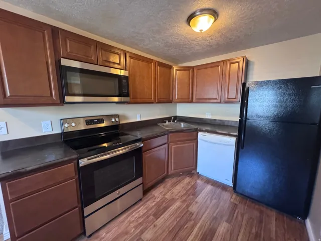 Kitchen featuring wood-finish flooring, dark countertops, and warm-toned cabinetry